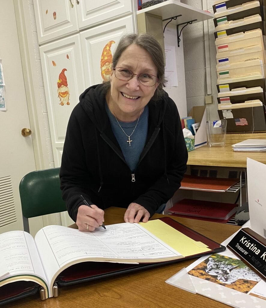 Smiling woman signing a document at her desk.