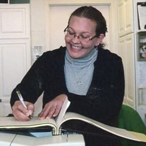 Woman smiling and writing in book.