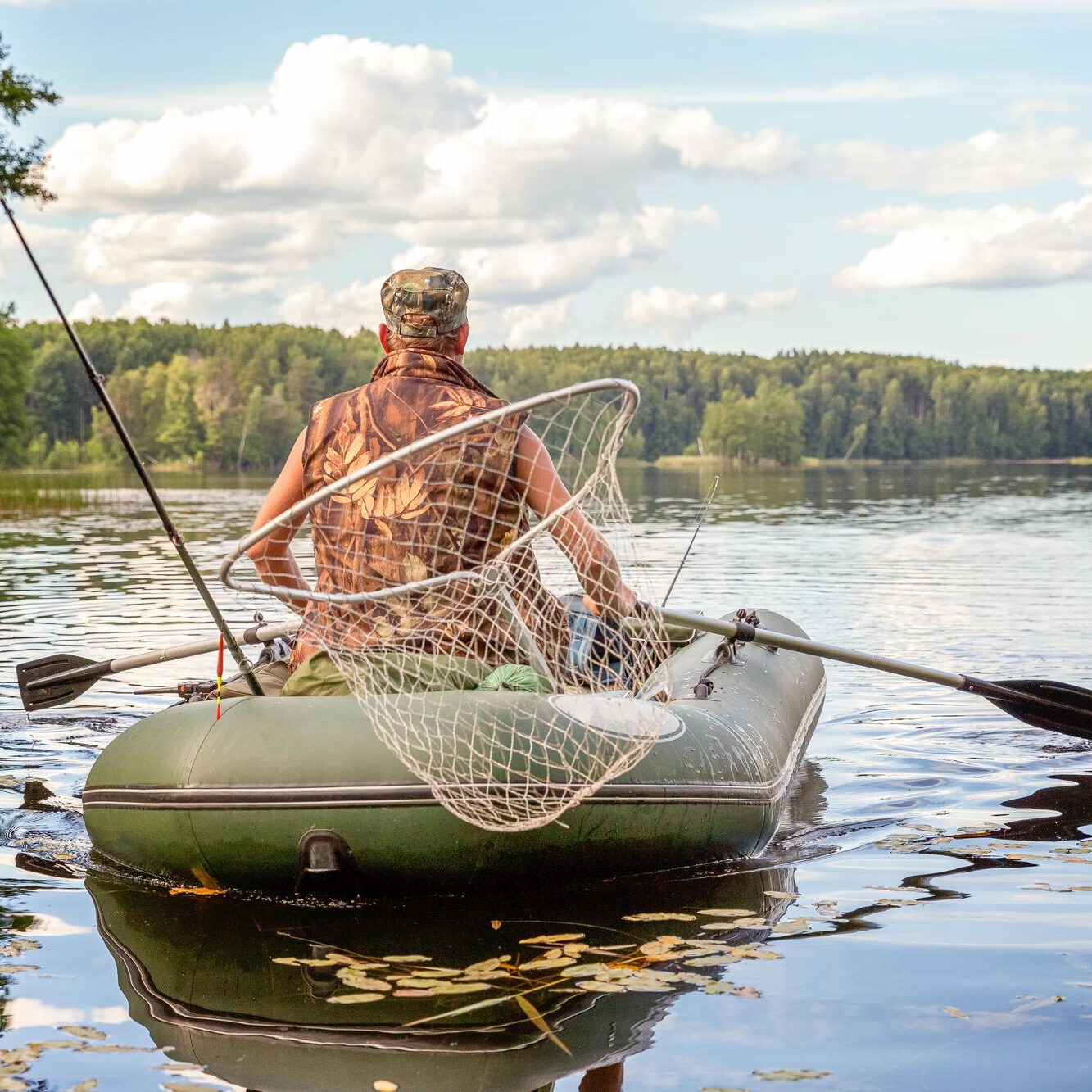 Fisherman in inflatable boat on calm lake